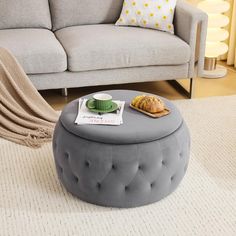 a living room with a gray ottoman and coffee table