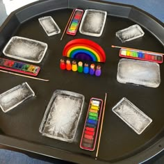 there are many different colored crayons on the trays and in front of them is a rainbow