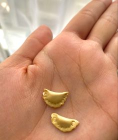 two small gold pieces in the palm of someone's hand, one is shaped like a bird