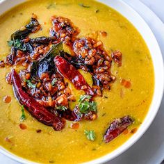 a white bowl filled with yellow soup and garnished with toppings on top