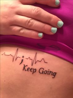 a woman's stomach with the words keep going tattooed on her side and heartbeat