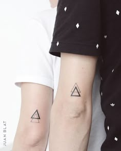 two people with matching tattoos on their arms, one is holding the other's arm