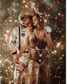 a man and woman dressed up as astronauts in space with stars all around them, posing for the camera