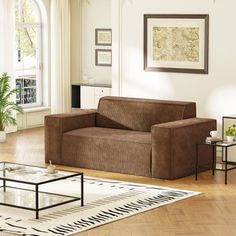 a living room filled with furniture next to a large window and a rug on top of a hard wood floor