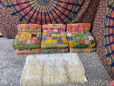 a group of colorful pillows sitting on top of a floor next to a wall covered in fabric