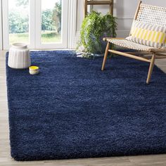 a blue rug in a living room with a chair and potted plant on the floor