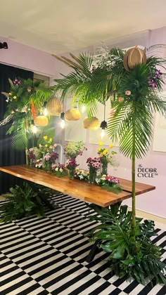 a table topped with lots of potted plants next to a wall filled with lights