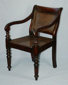 a wooden chair with wicker back and arm rests against a white backdrop