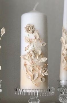 three white candles with flowers on them sitting next to each other