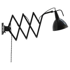 a black metal wall light with a long arm and an upside down lamp on it's side