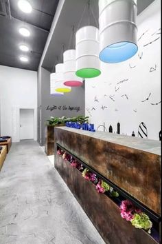 the interior of an office building with flowers on the counter and hanging lights above it