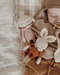 a baby sleeping on top of a blanket with stuffed animals around it's neck