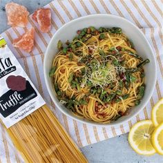 a bowl of pasta with asparagus and sun dried oranges next to it