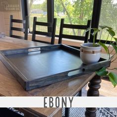 an empty tray sitting on top of a wooden table next to a potted plant