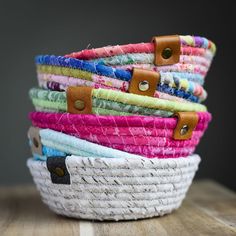 several woven baskets are stacked on top of each other in different colors and sizes, with leather handles