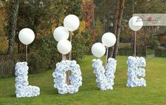 the letters are made out of paper flowers and white balloons in the shape of love