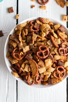 a bowl filled with cheetos and pretzels on top of a white table