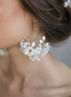 a close up of a person wearing earrings with flowers and pearls on the hoops