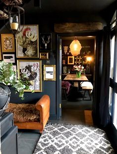 a living room filled with furniture and pictures on the wall next to a doorway that leads to a dining room