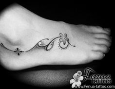 a small foot tattoo with flowers on the top and bottom part of it, in black and white