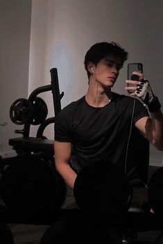 a man taking a selfie in front of a gym machine with headphones on