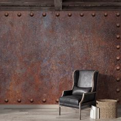 a black chair sitting in front of a rusted metal wall