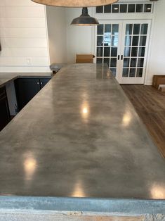 a kitchen counter top with lights hanging from it's ceiling and cabinets in the background