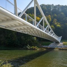 a white bridge over a river next to a forest