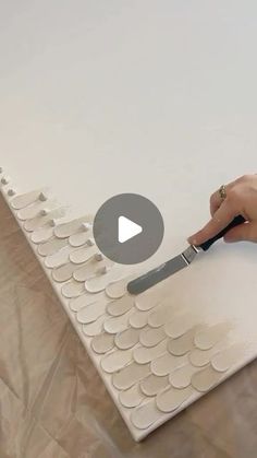 a person is using a knife to cut out circles on a sheet of white paper