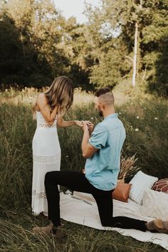 a man kneeling down next to a woman on a blanket