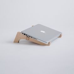 an apple laptop sitting on a wooden stand