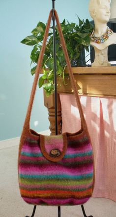 a multicolored purse sitting on top of a table next to a potted plant