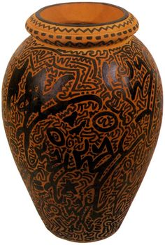 an orange and black vase with designs on it