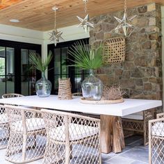 a table with chairs and vases on top of it in front of a stone wall