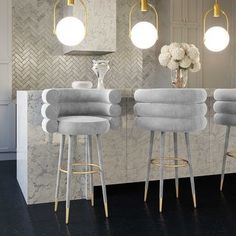 three light blue stools in front of a marble bar with flowers on the counter