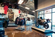 a motorcycle is on display in a shop with other items and clothing hanging from the ceiling