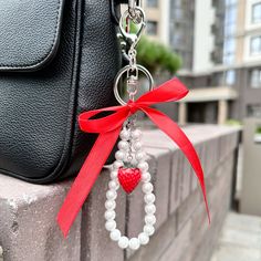 a handbag hanging from the side of a wall with a red ribbon attached to it