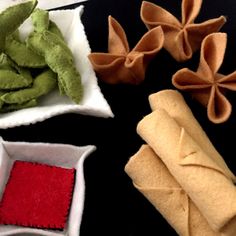 four different types of felt flowers in small bowls and napkins on a black surface