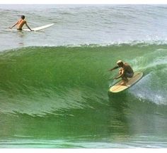 two people on surfboards riding the waves in the ocean, one man is surfing