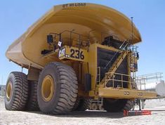 a large yellow dump truck parked on top of a dirt field