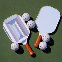 two ping pong paddles and three balls on a green surface with a mirror