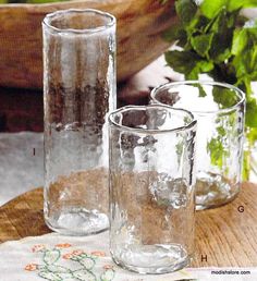 three glass vases sitting on top of a wooden table