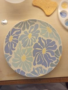 a blue and white plate sitting on top of a wooden table next to two spoons