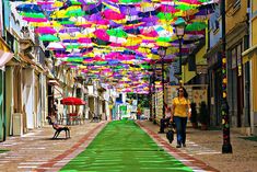 a woman walking down a street with lots of umbrellas hanging from the ceiling above her