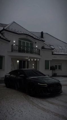 a black sports car parked in front of a white house with snow on the ground