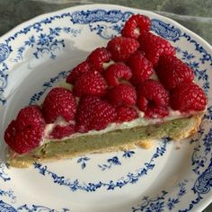 a piece of cake with raspberries on top sits on a blue and white plate