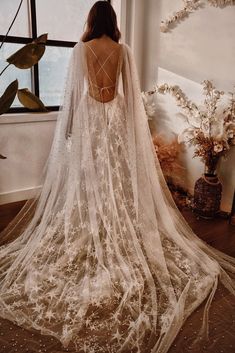 the back of a woman's wedding dress in front of a window