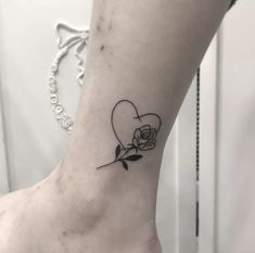 a small tattoo on the ankle of a woman's foot with a rose and heart