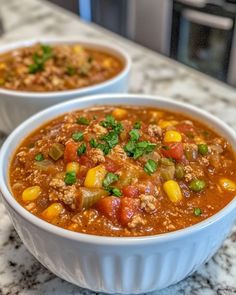 two bowls of chili and corn soup on a counter