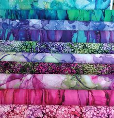 an assortment of colorful fabrics with different patterns and colors on them, including pink, green, purple, and blue